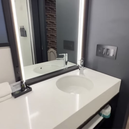 Bathroom quartz vanity countertop and metal frame mirror in Aloft by Marriott hotel