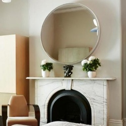Round metal framed mirror over fireplace