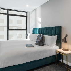 Fully upholstered bed and metal base nightstand in Meriton Suites Sydney